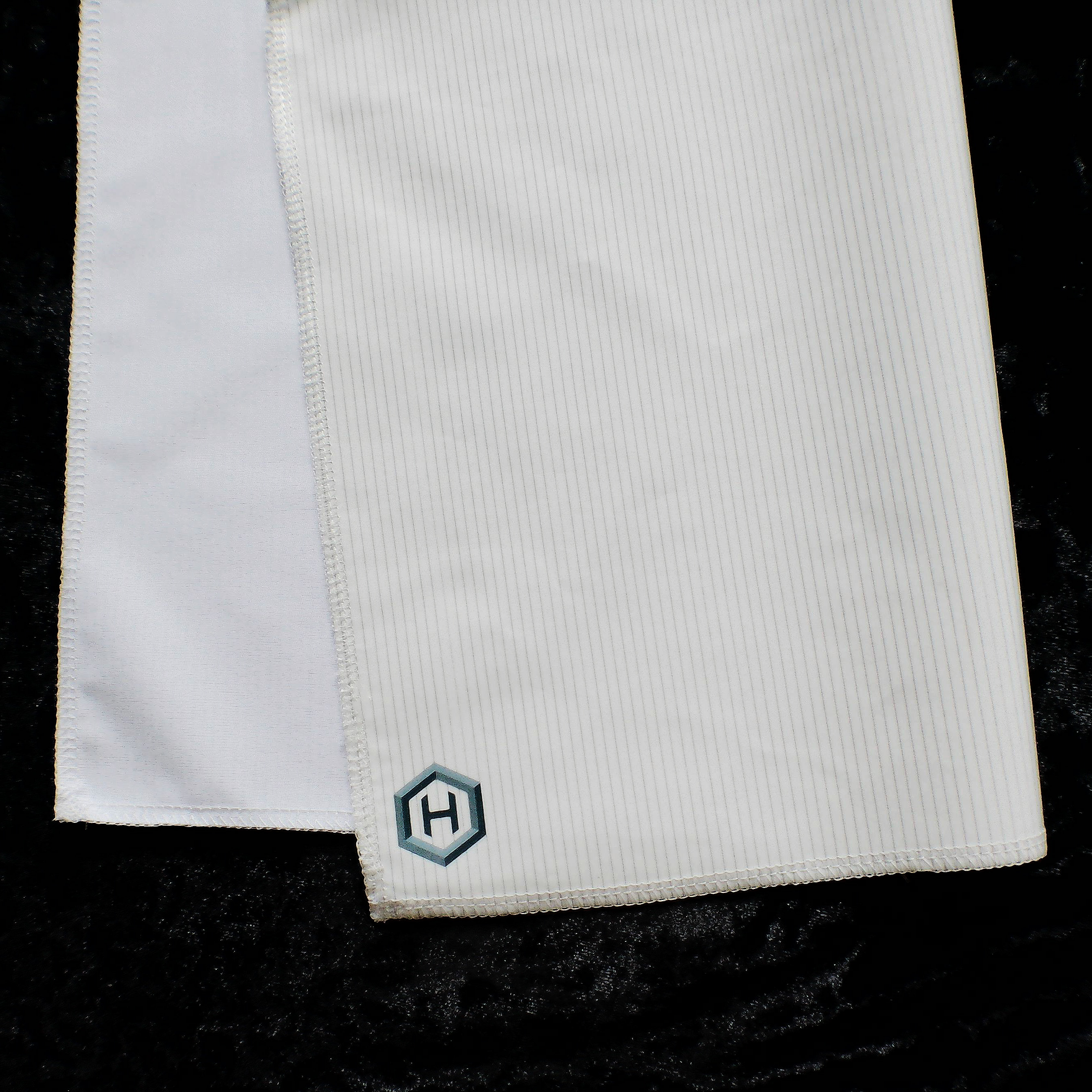 Actual HexTex fabric showing the smooth organic cotton face beside the fine pinstripe graphene side, marked with the hexagonal H logo